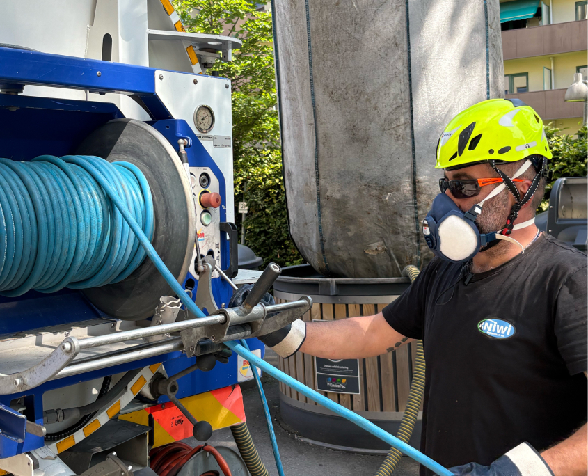 Tekniker fra NIWI sjekker sikkerhetsmekanismer på en delvis nedgravd avfallsbrønn i forbindelse med renhold.