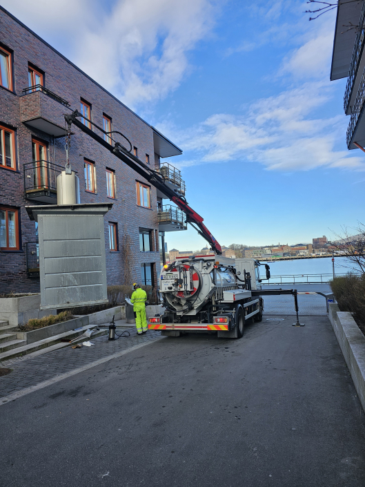 Helt nedgravd avfallsystem blir heiset opp for vask og reparasjon av Niwi Miljøtiltak spesialbygde vaskebil foran borettslag i Oslo